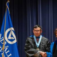 Provost Mili shakes hands with man on stage
